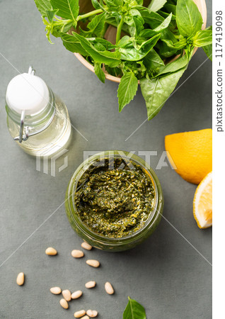 Traditional Italian pesto in a jar with green basil, pine nuts, cheese and olive oil  117419098
