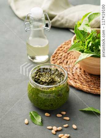 Traditional Italian pesto in a jar with green basil, pine nuts, cheese and olive oil Traditional Italian pesto in a jar with green basil, pine nuts, cheese and olive oil 117419100