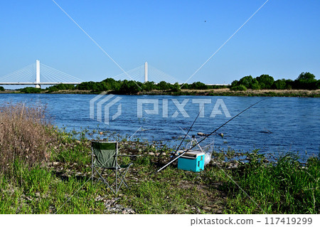A fisherman places his fishing rod on a rod stand and waits for a bite 117419299