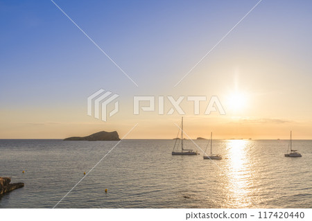 Sailboats at sunset off Ibiza coast, golden sea and islands Sailboats at sunset off Ibiza coast, golden sea and islands 117420440