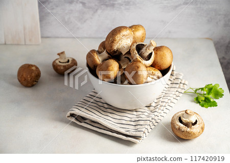 Raw champignon in a bowl on bright background, button mushrooms. Vegan protein.  117420919