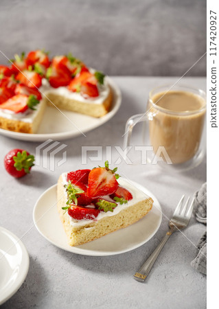 Slice of sponge cake with fresh strawberries, served with cup of coffee 117420927