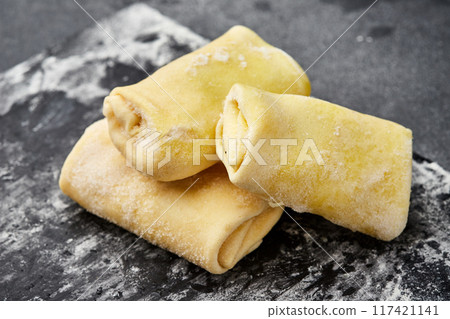 Freshly rolled stuffed crepes, ready for cooking, showcasing traditional homemade preparation Freshly rolled stuffed crepes, ready for cooking, showcasing traditional homemade preparation 117421141