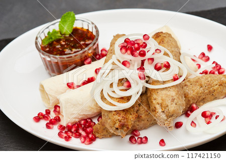 Traditional grilled kebab with pomegranate, onions, spicy sauce for flavorful culinary experience 117421150