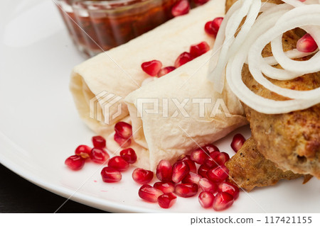 Traditional grilled kebab with pomegranate, onions, spicy sauce for flavorful culinary experience 117421155