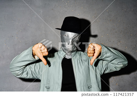 Mystery man with duct tape face showing thumb down sign gesture Mystery man with duct tape face showing thumb down sign gesture 117421357