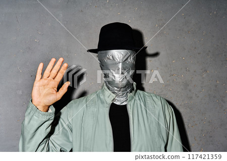 Mystery man with duct tape face raised hand in greeting 117421359