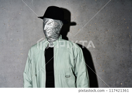 Mystery man in hat with duct tape face wrap on gray background. Mystery man in hat with duct tape face wrap on gray background. 117421361