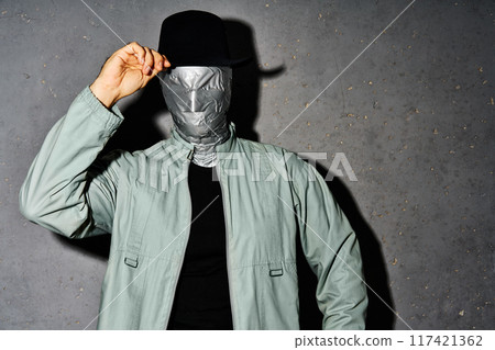 Mystery man with duct tape face greets by raising his hat 117421362