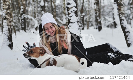 A girl playing with her Jack Russell Terrier dog in the snow. 117421464
