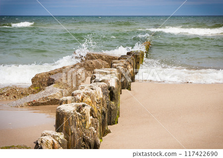 Landscape of beach and wooden breakwaters with sea waves. Stormy day at sea Landscape of beach and wooden breakwaters with sea waves. Stormy day at sea 117422690
