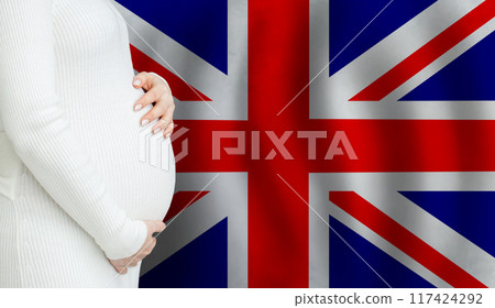 Demographics and pregnancy in UK concept. Close-up of pregnant woman belly against Flag 117424292