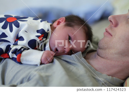 Curious newborn baby lying on father's chest. Childhood, new family and baby protection concept 117424323
