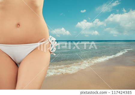 Woman relaxing on tropical resert. Hips bikini stomach abs close-up 117424385