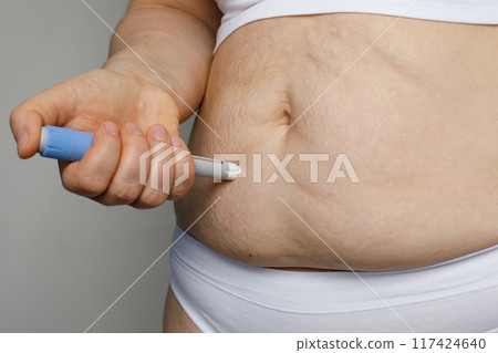 Young woman doing insulin injection pen, close-up. Diabetic patient  117424640