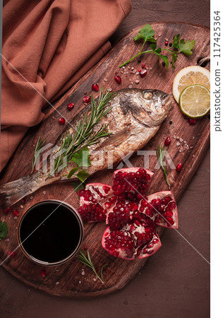 Fried dorado fish, with spices and herbs, on a wooden board, pomegranate sauce, close-up, no people, Fried dorado fish, with spices and herbs, on a wooden board, pomegranate sauce, close-up, no people, 117425364
