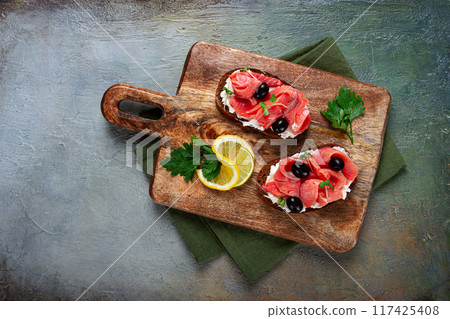 sandwiches with cream cheese, chum salmon, cold smoked, grain bread, on a cutting board, top view, breakfast, lemon and parsley, no people, sandwiches with cream cheese, chum salmon, cold smoked, grain bread, on a cutting board, top view, breakfast, lemon and parsley, no people, 117425408