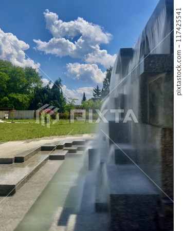 Fountain in the park on a background of blue sky with clouds. Japanese garden at Silesian park, Chorzow, Poland Fountain in the park on a background of blue sky with clouds. Japanese garden at Silesian park, Chorzow, Poland 117425541