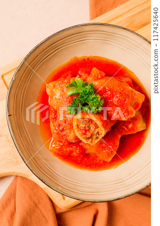 Stuffed cabbage rolls, with minced meat, in tomato sauce, on a beige background, top view, no people, selective focus. Stuffed cabbage rolls, with minced meat, in tomato sauce, on a beige background, top view, no people, selective focus. 117425640