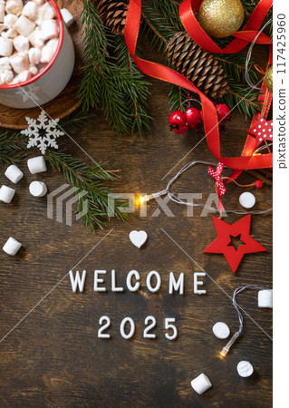 Winter, christmas lights, cozy cup hot chocolate drink with marshmallow on wooden table background. Seasonal relaxing and still life concept. View from above with english text welcome 2025. Winter, christmas lights, cozy cup hot chocolate drink with marshmallow on wooden table background. Seasonal relaxing and still life concept. View from above with english text welcome 2025. 117425960