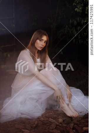 Pale woman in white dress on the ground, dark mystery scene Pale woman in white dress on the ground, dark mystery scene 117425991
