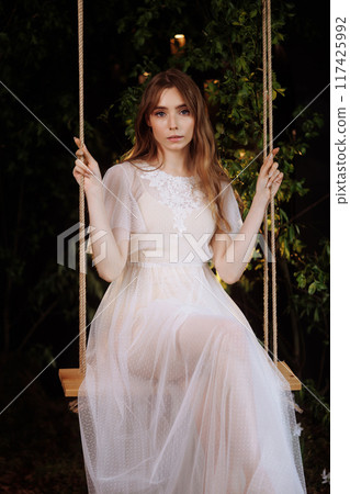Elegant woman on wooden swing. Elegant woman on wooden swing. 117425992
