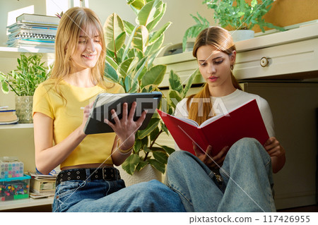 Two teenage girls students studying sitting on the floor at home 117426955