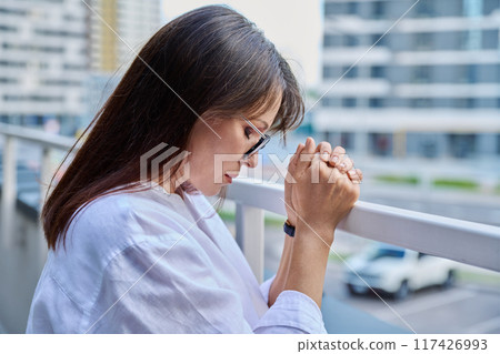 Mature serious woman holding hands in prayer Mature serious woman holding hands in prayer 117426993