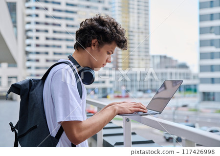 Young handsome male using laptop computer, modern city skyscrapers background 117426998