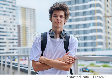 Handsome young man looking at camera outdoors, modern skyscrapers urban style background 117426999