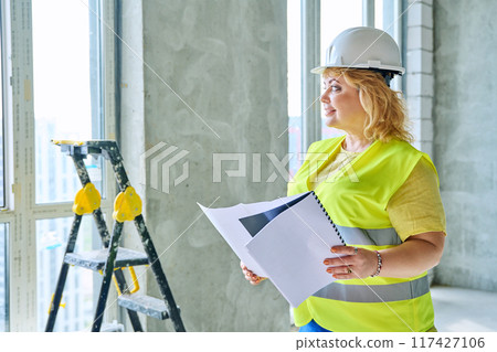 Technical profession woman in safety vest helmet working on construction 117427106