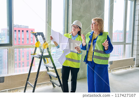 Two female industrial workers at construction site discussing work plans Two female industrial workers at construction site discussing work plans 117427107