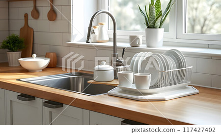 Dish rack holds many dishes and cups against wooden countertop, white wall tiles, sink and faucet. Budget and lightweight antimicrobial dish drainer with drain board at modern scandinavian kitchen Dish rack holds many dishes and cups against wooden countertop, white wall tiles, sink and faucet. Budget and lightweight antimicrobial dish drainer with drain board at modern scandinavian kitchen 117427402