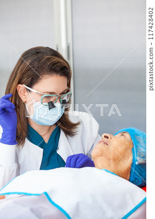Dermatologist carrying out a skin biopsy on the face of a senior adult patient 117428402