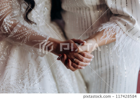 Touching moment of a mother and bride holding hands, capturing love and support on the wedding day 117428584