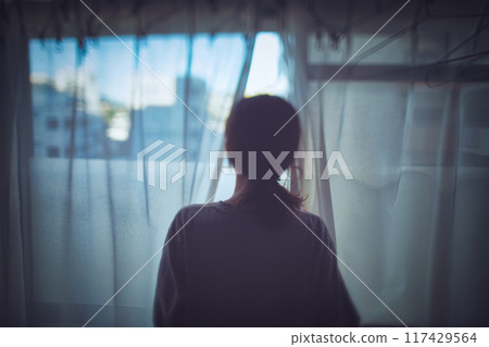一個女人透過窗戶向外看的後視圖 117429564