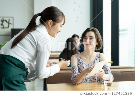 A young woman serving foreign tourists at a cafe 117431589