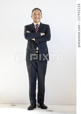 一位 60 多歲、雙臂交叉微笑的商人 117432228