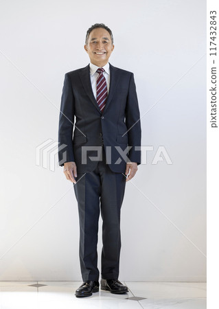 一位 60 多歲的商人對著鏡頭微笑,全身 一位 60 多歲的商人對著鏡頭微笑,全身 117432843