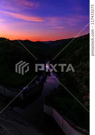Summer 2024 Evening view of Nunome Dam in eastern Nara City. The sky is burning on the north (valley) side of the dam. The sky is a vivid color of deep blue and vermilion on the mountainside. 117433273