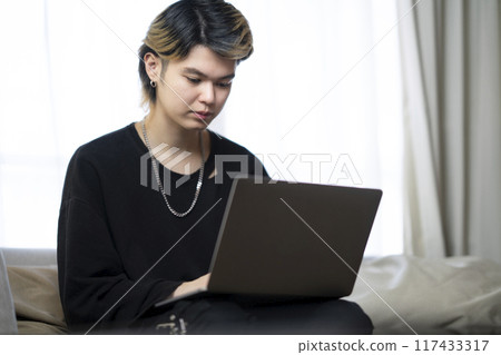 A man in his twenties working on a laptop A man in his twenties working on a laptop 117433317