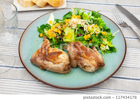 Fried quail garnished with portion of fresh vegetable salad 117434178