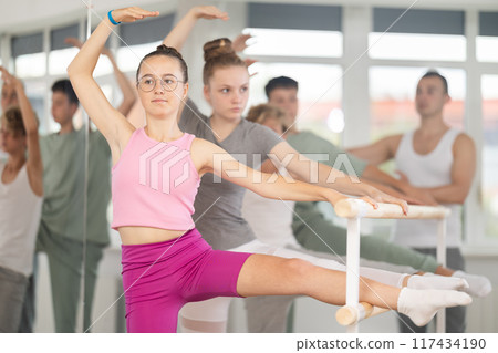 Teenage girl practicing leg stretching exercise during ballet classes 117434190