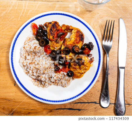 Boiled buckwheat in bowl with chicken legs. Dinner table, healthy food concept Boiled buckwheat in bowl with chicken legs. Dinner table, healthy food concept 117434309