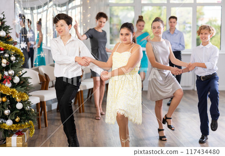 Celebrating Christmas in dance class - girls and boys dance the Moresco dance near New Year tree 117434480
