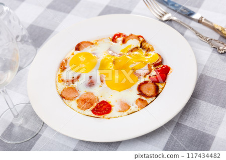 Homemade hearty breakfast - fried eggs with frankfurter and tomato 117434482