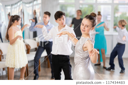 Happy adolescent girl dancing twist during college holiday event 117434483