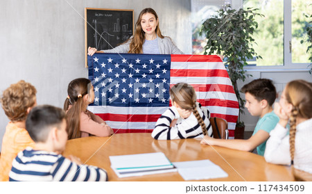 Teacher showing USA flag to group of schoolchildren 117434509