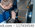 A worker repairs a broken indicator light on a vehicle, examining the part closely 117434540