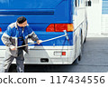 A focused worker scrubs the back of a bus with a mop and water, ensuring cleanliness 117434556